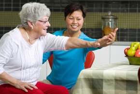 Lady helping an old woman to do physiotherapy